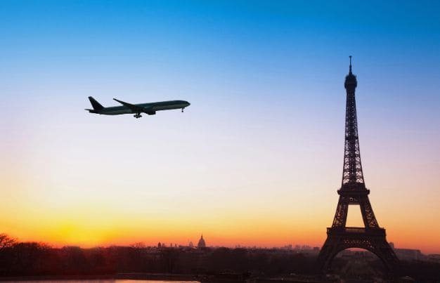 Airplane flying over Eiffel Tower symbolizing transfer from Paris airports to Disneyland Paris